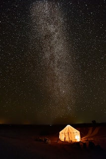 A cozy luxury tent glowing warmly under a star-filled Nubra Valley sky.