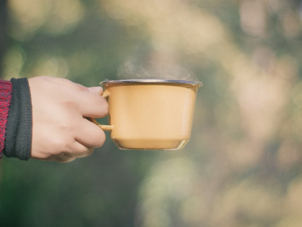 person holding brown teacup