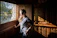 A happy middle-aged woman standing by a newly installed window with sunlight streaming in.