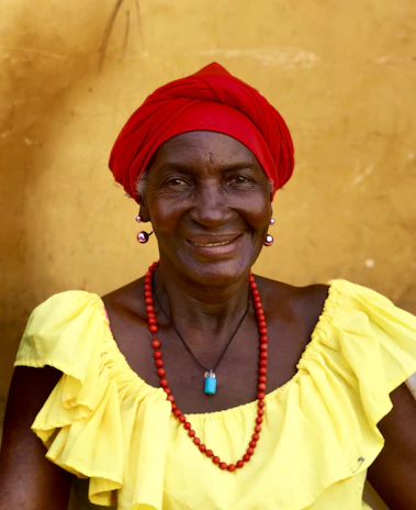 A senior woman wearing a medical alert necklace while smiling comfortably at home.
