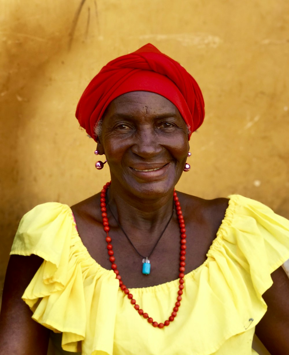 laughing woman wearing beaded necklace and red hat during daytime