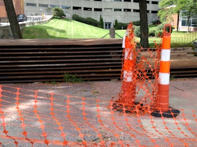 Backfilling around newly installed foundation supports with safety cones nearby.