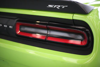 Rear diffuser and spoiler on a dark-colored Dodge Challenger under moody industrial lighting.