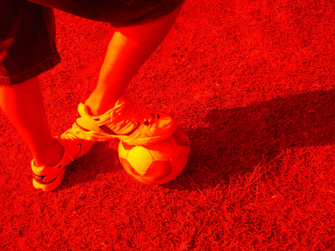 Cinematic shot of a soccer influencer training intensely on a dew-covered pitch at dawn.