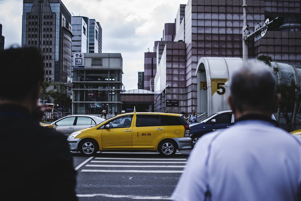men walking on pedestrian towrds yellow SUV