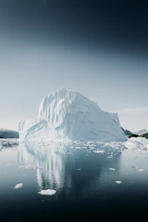 A serene iceberg floating in calm waters under a twilight sky, with a golden pen nib subtly visible beneath the surface.