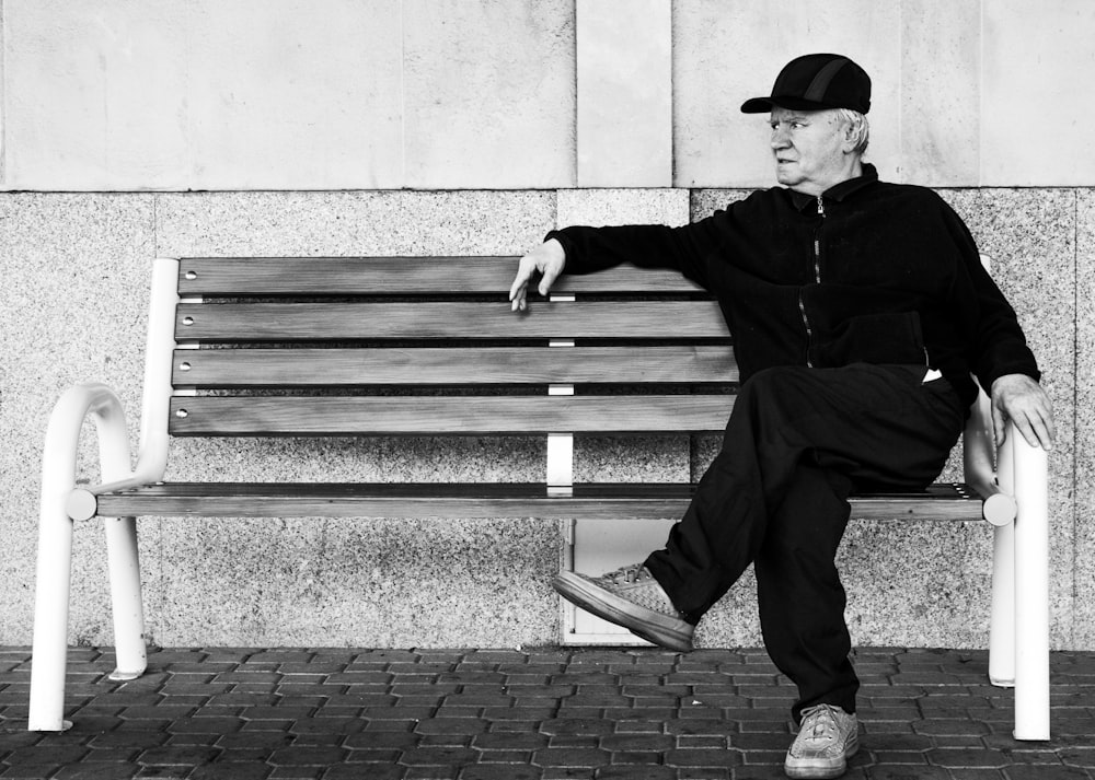 greyscale photo of man sitting on bench