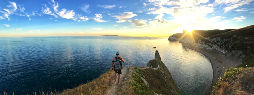 panoramic photography of man walking on cliff