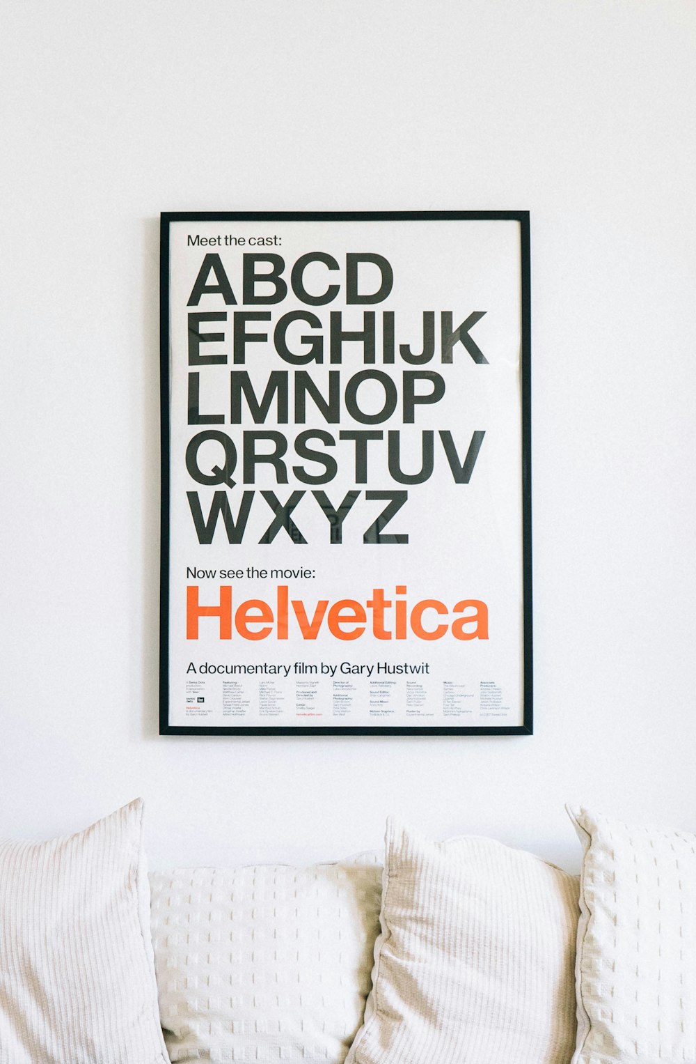 poster do alfabeto Helvetica montado na parede acima do sofá