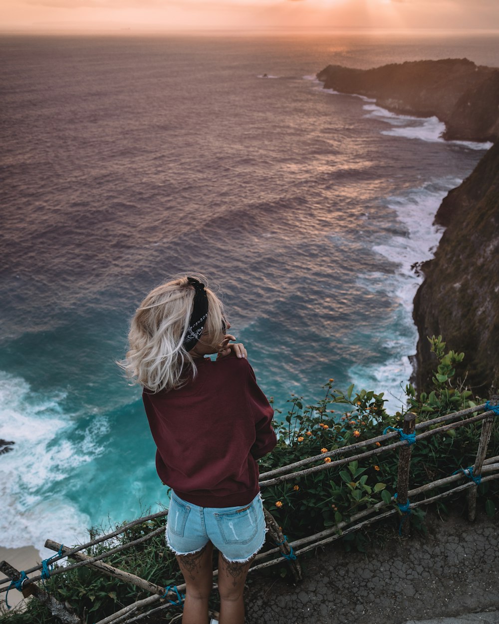 woman standing on cliff near body of water