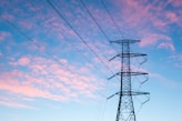 black electric pylon under orange clouds during daytime