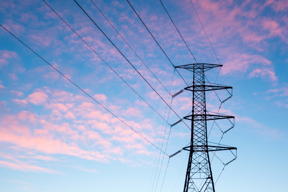 black electric pylon under orange clouds during daytime