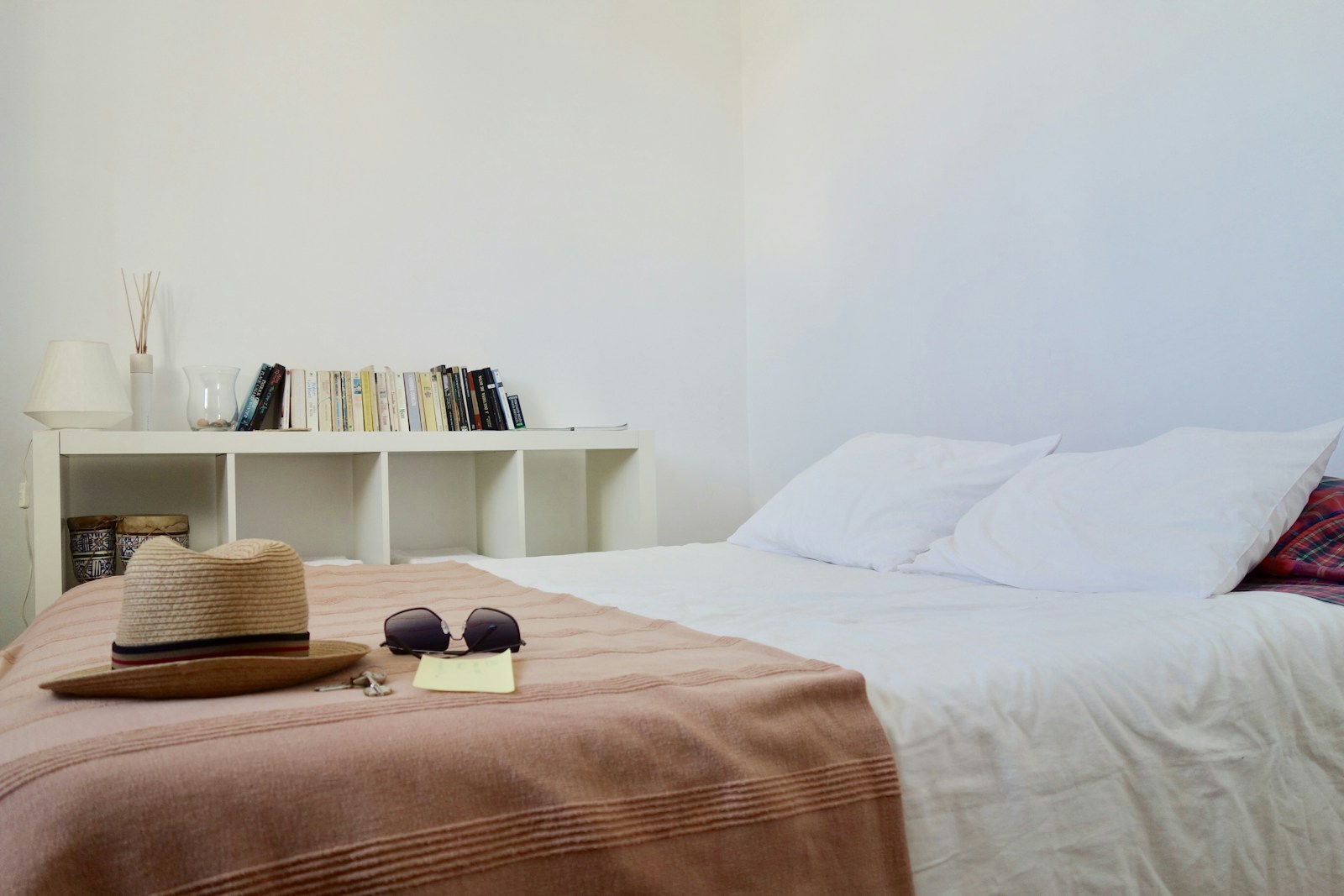 low bookshelf used as headboard and nightstand in small bedroom
