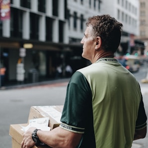 man carrying cardboard boxes during daytime