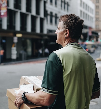 man carrying cardboard boxes during daytime