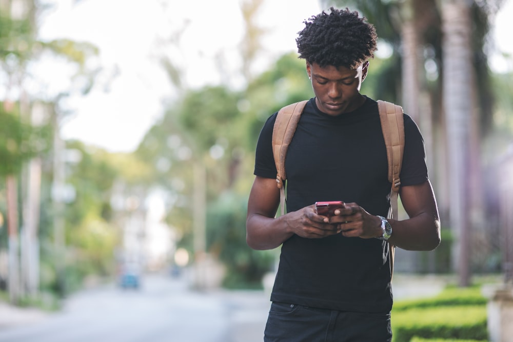 man in black shirt holding red smartphone