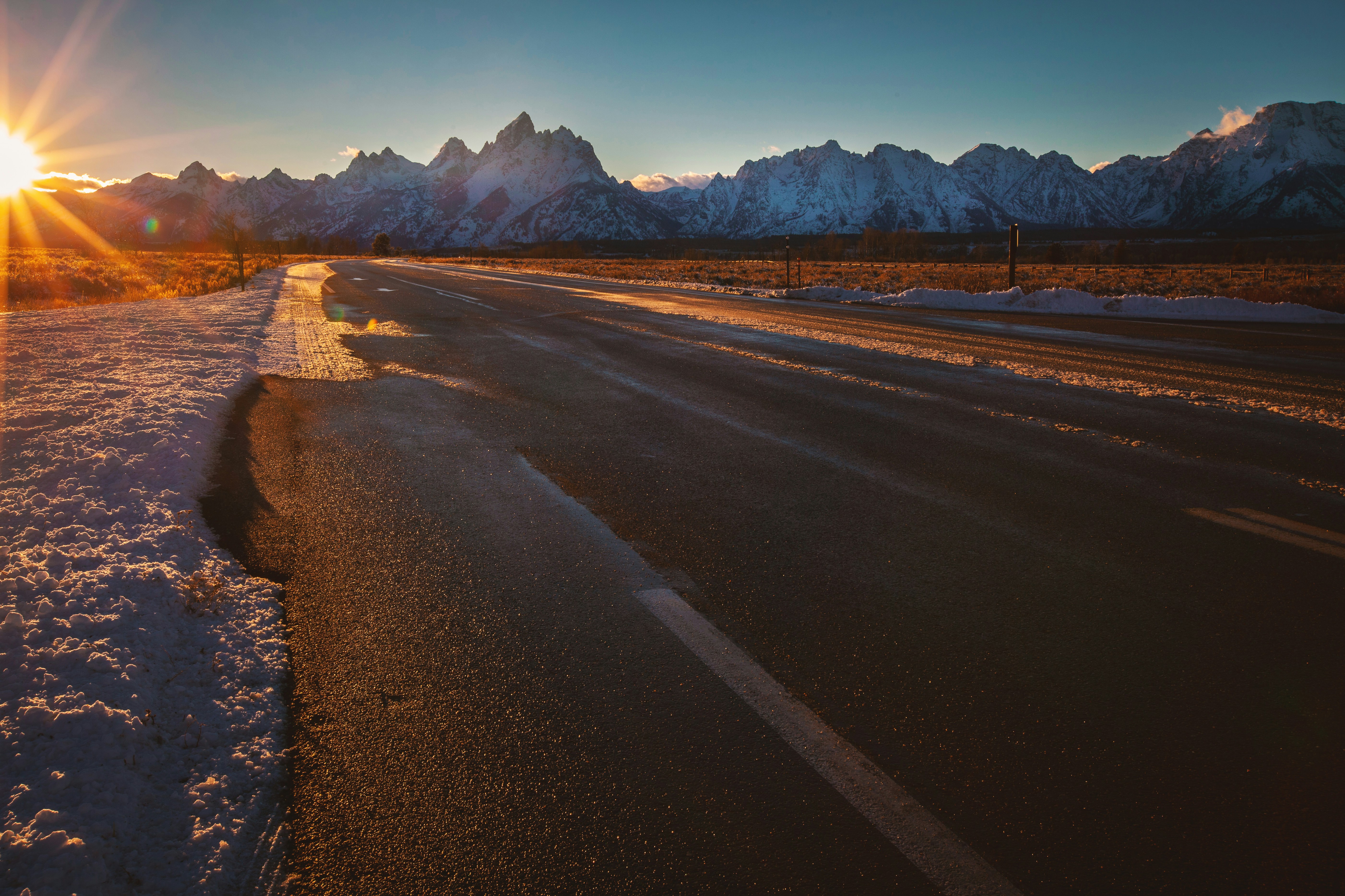 Carretera vacía cerca de montañas cubiertas de hielo durante la hora dorada