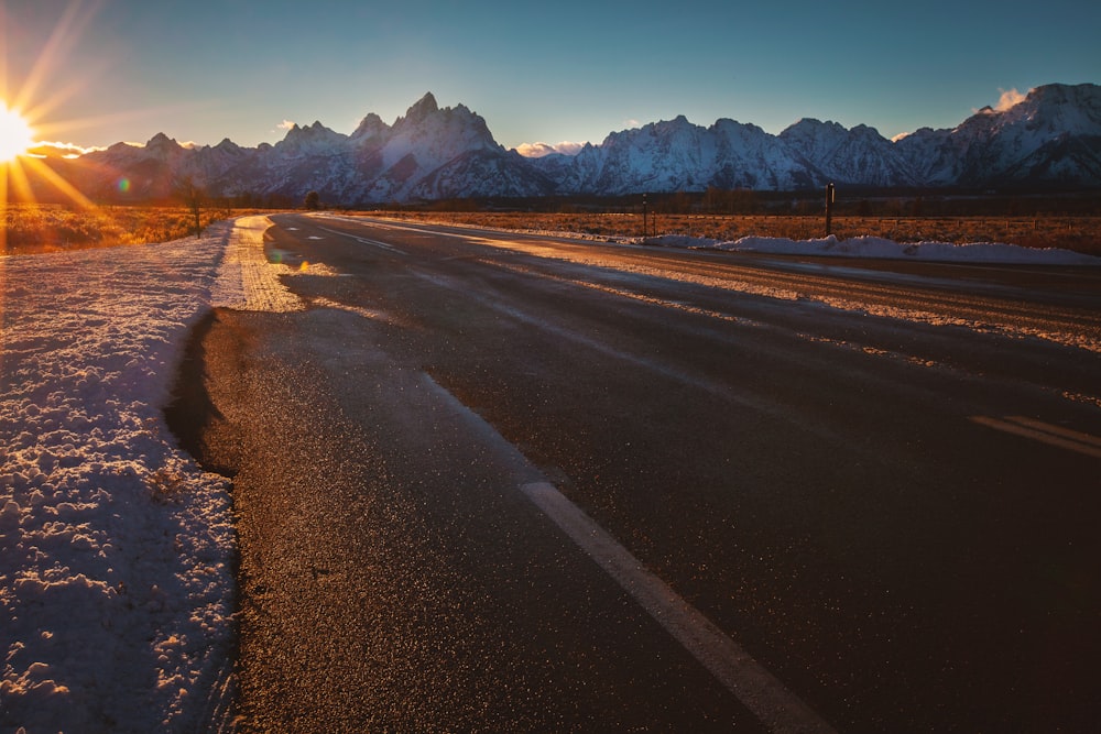 골든 아워 동안 얼음 덮인 산 근처의 텅 빈 도로