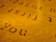 Artistic shot of textured paper with delicate gold leaf details and off-white background.