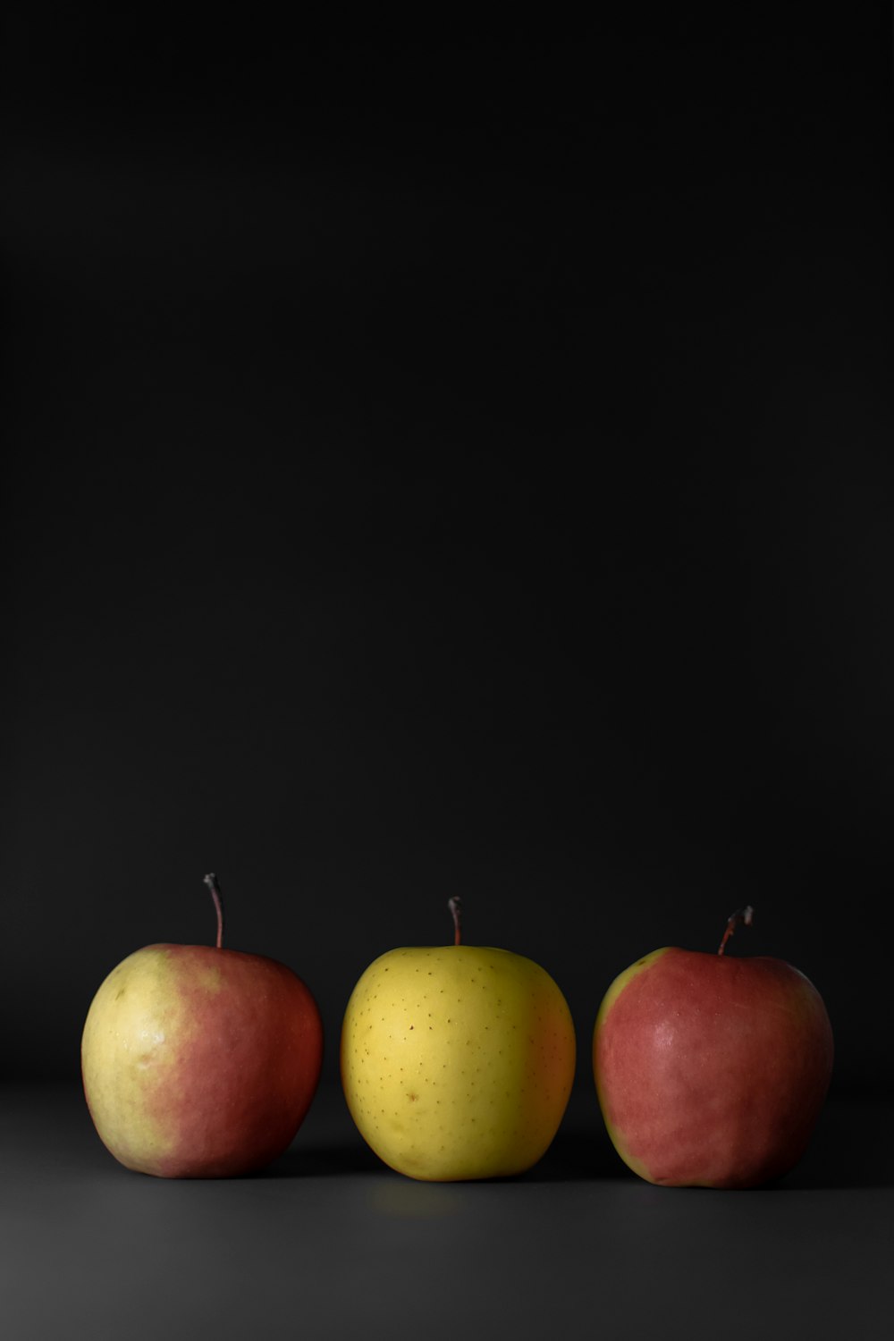 three apples behind black background