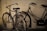 Two vintage bicycles are leaned against a weathered brick wall. The bicycles appear old and rusty, with worn-out seats and tires. The scene has a nostalgic and timeless feel.
