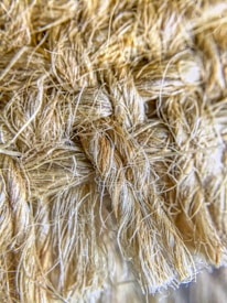 A close-up view of a textured, woven fiber material with tightly interwoven strands. The fibers appear soft yet robust, with a natural, earthy hue.