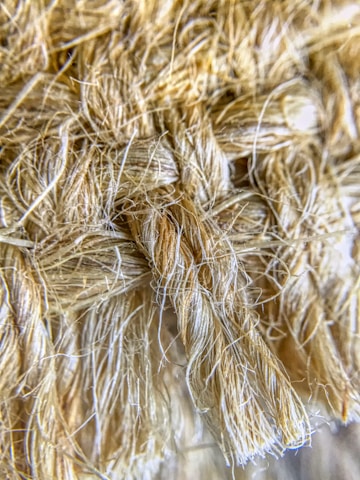 A close-up view of a textured, woven fiber material with tightly interwoven strands. The fibers appear soft yet robust, with a natural, earthy hue.