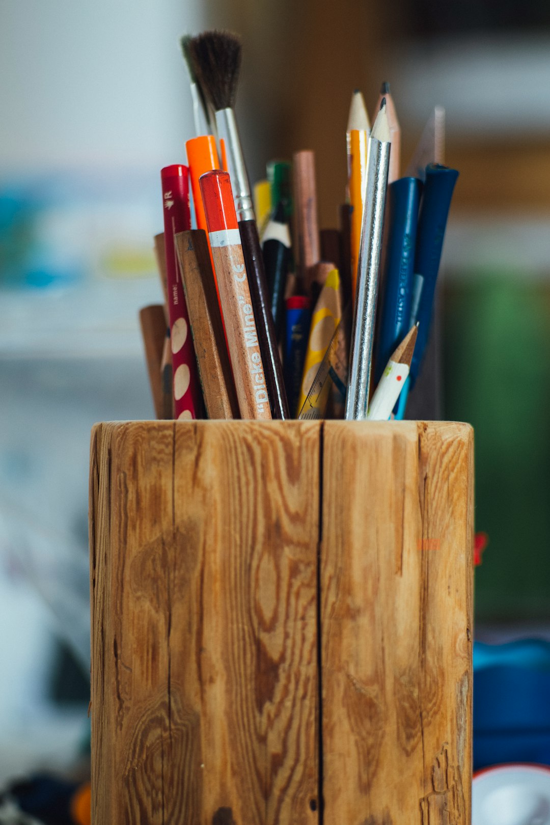 Wooden cup holder with colorful pencils and paintbrushes
