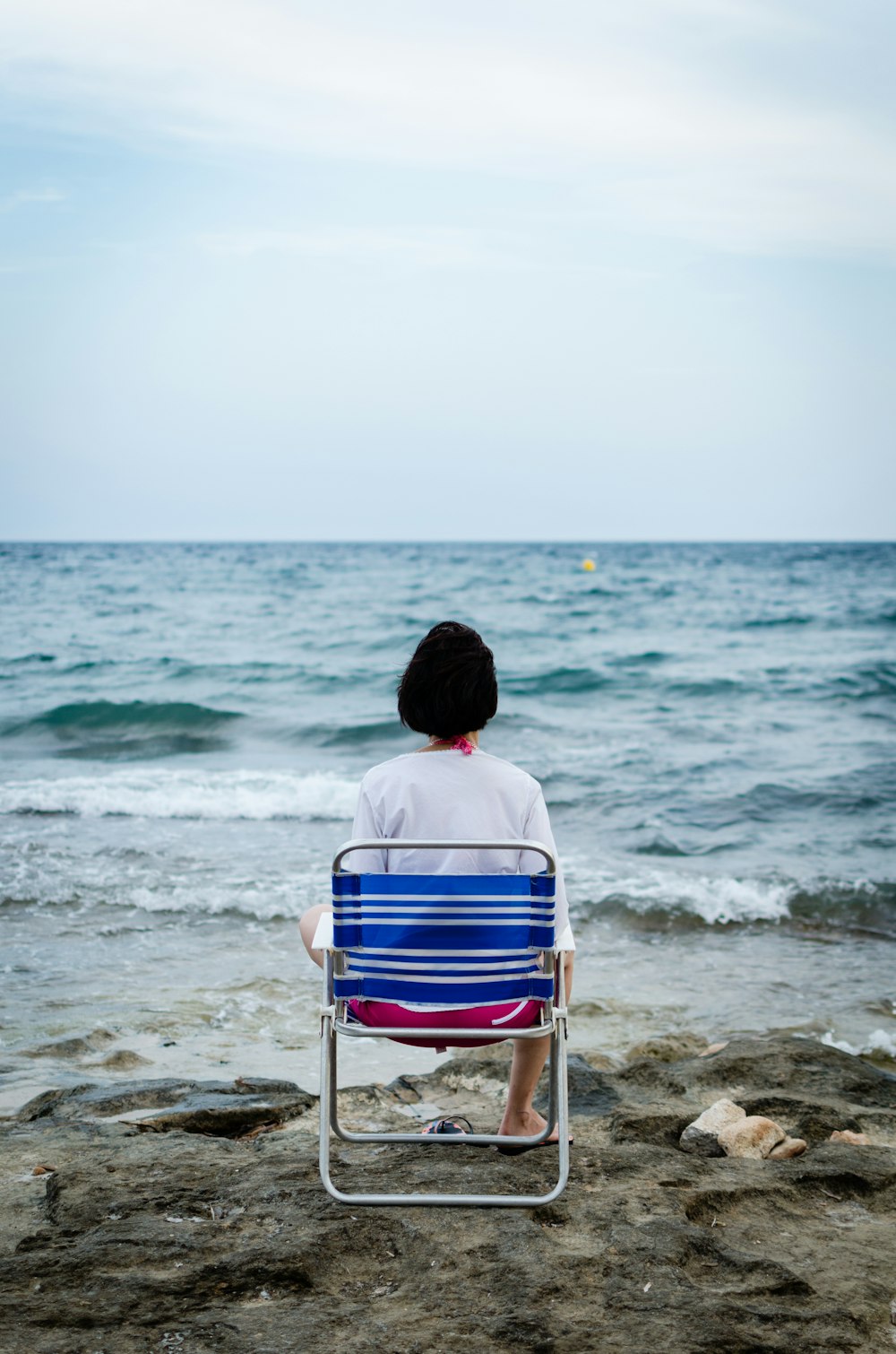 woman sitting on folding chair beside seashore