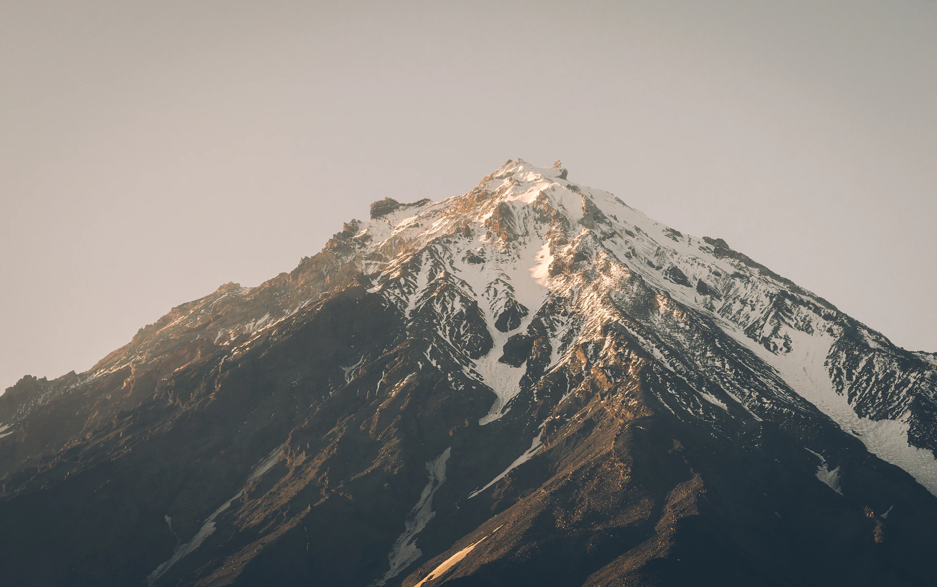 A crisp, high-resolution photo capturing the serene beauty of Liberty Peak at sunrise, with soft golden light illuminating the rugged landscape.