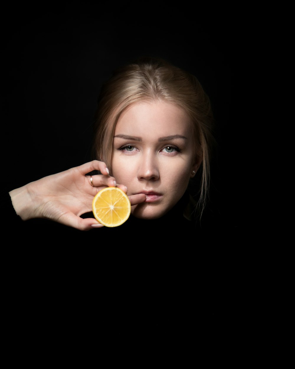 woman holding slice of orange fruit