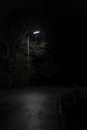 A darkened street at night with a single flickering streetlight.