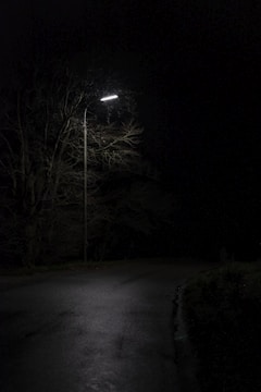 A darkened street at night with a single flickering streetlight.