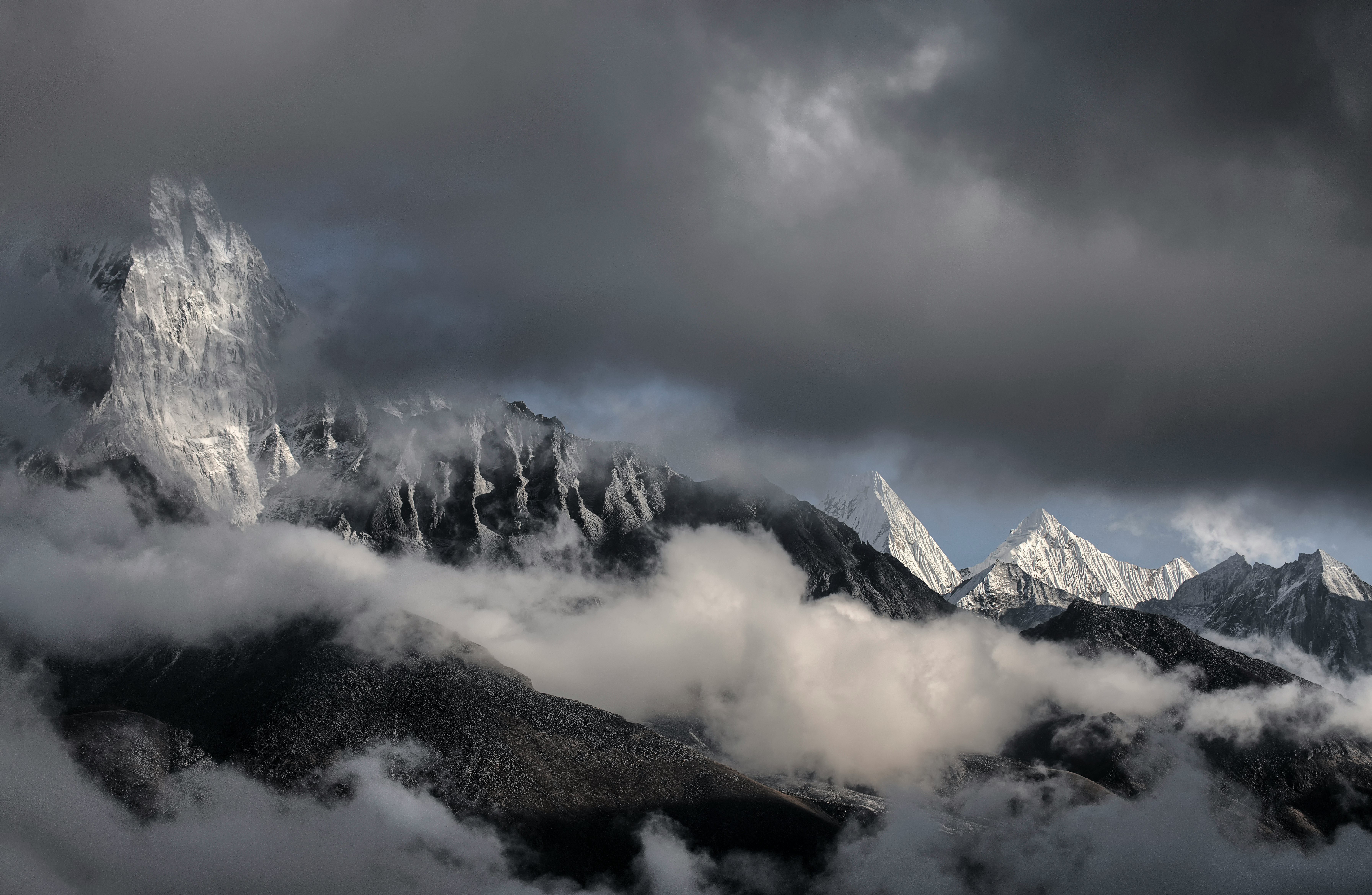 snowy mountain peaks under dark clouds