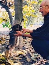 A volunteer gently holding a rescued dog outdoors.