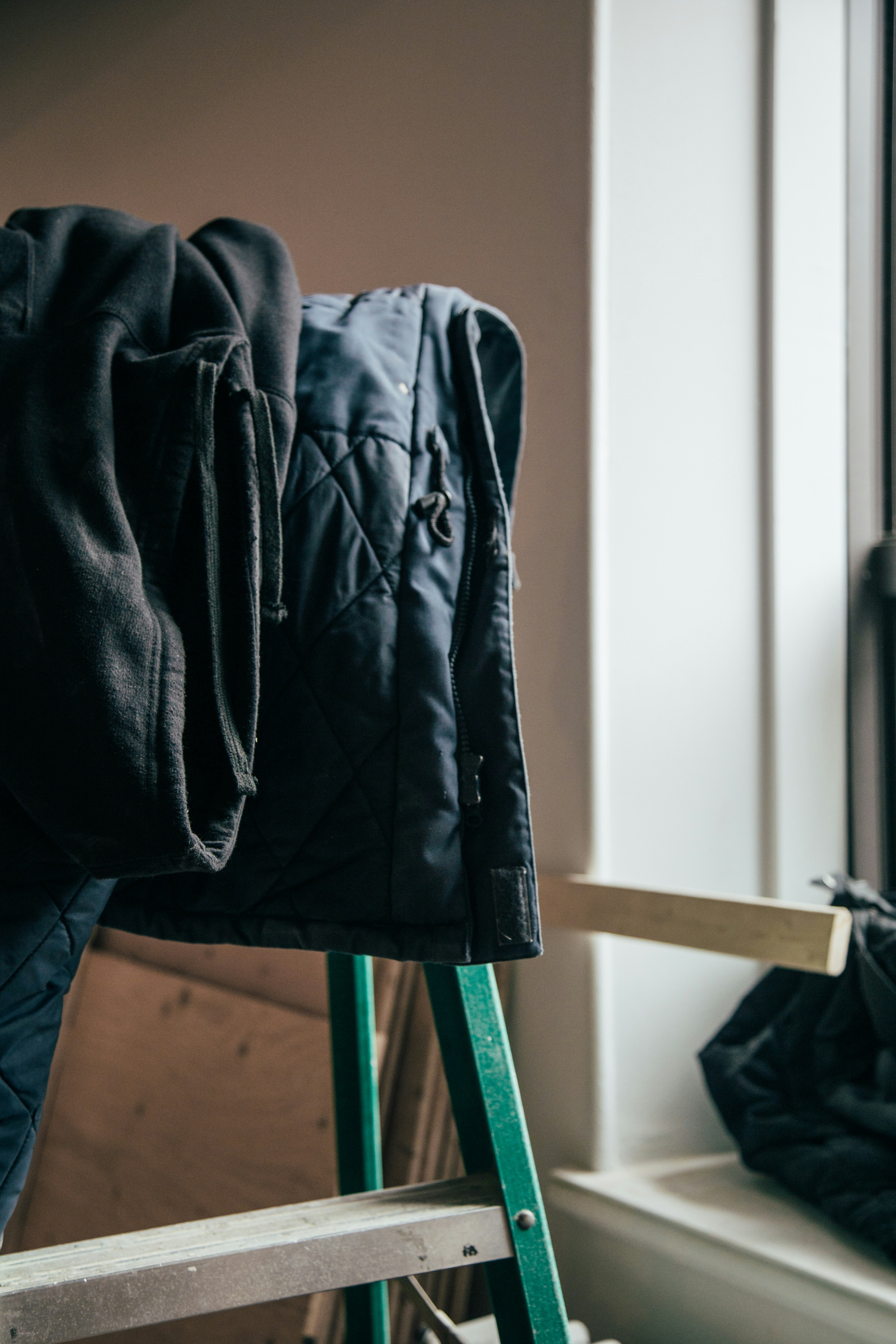 black and blue bubble coat hanging on metal ladder