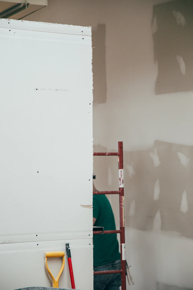 Worker smoothing drywall patch in interior wall
