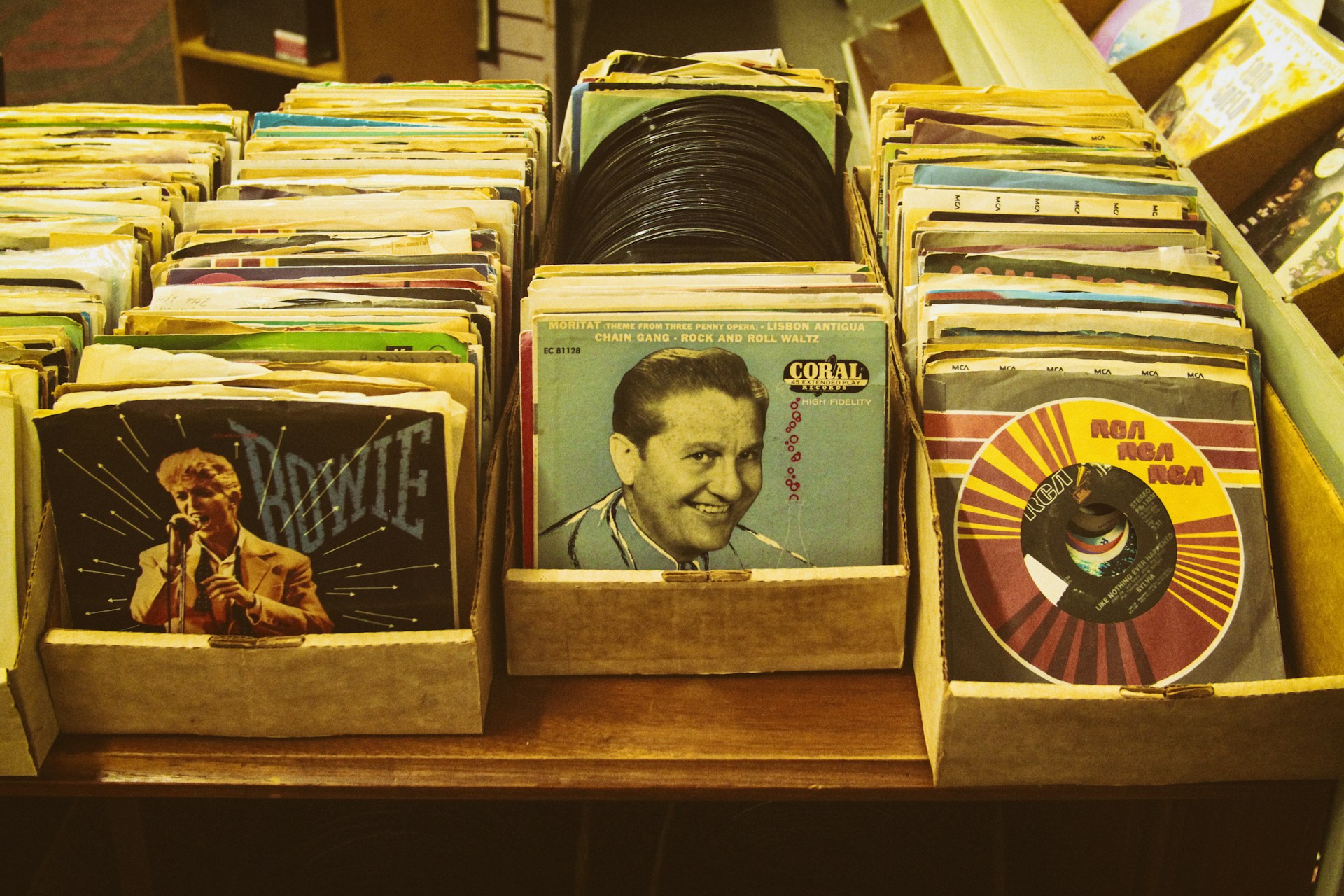 An assortment of rare vinyl records stacked casually, with a focus on their colorful, worn covers that tell stories of the past.