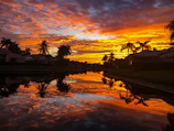 A stunning beachfront villa at sunset with vibrant orange skies.
