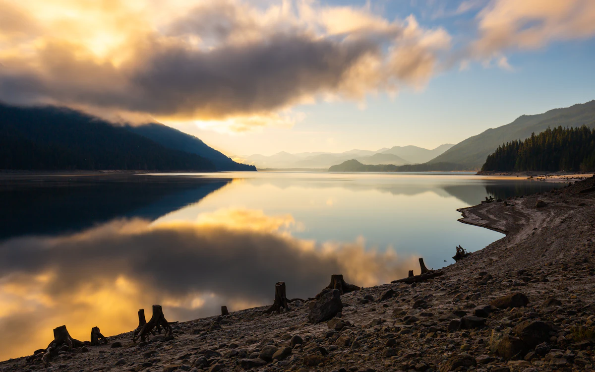 Kachess Lake near Easton in morning light, with tree stumps on the shore and forested ridges behind