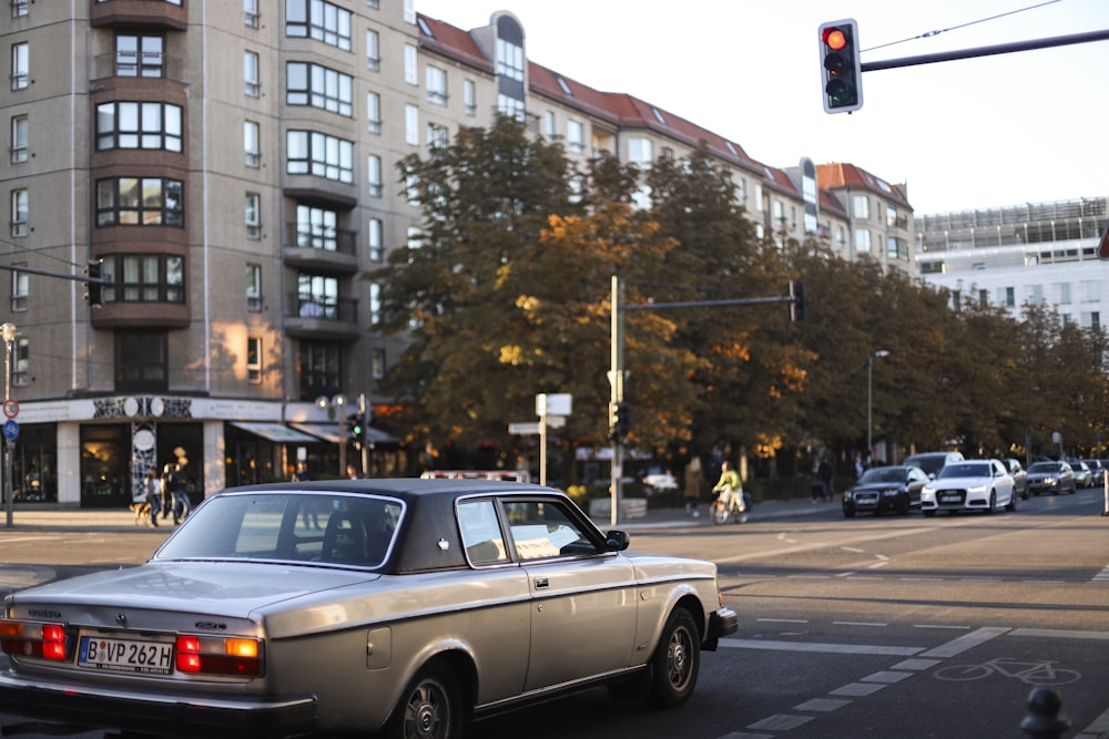 vehicle on road intersection stopping to red lights near brown buildings at daytime