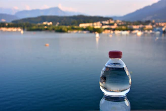 Close-up of a 6-liter disposable water bottle with droplets, set against a backdrop of mountain peaks.