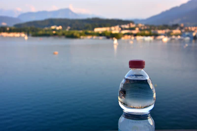 Close-up of a 6-liter disposable water bottle with droplets, set against a backdrop of mountain peaks.
