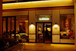 Exterior view of La Cascina restaurant with rustic wooden facade and soft evening glow.