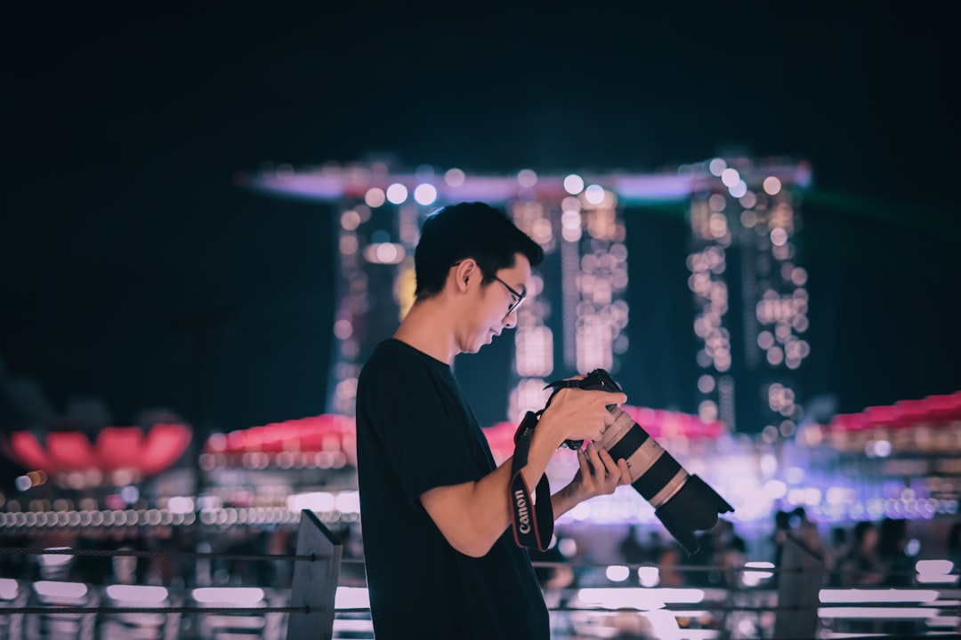 selective focus photography man holding Canon DSLR camera