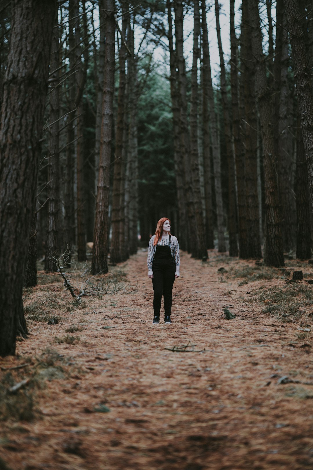 woman standing on dirt road surrounded by trees
