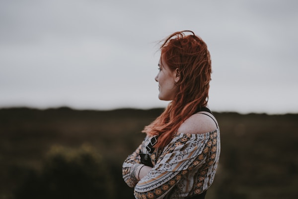 woman in white, orange, and black floral off-shoulder shirt crossing arms