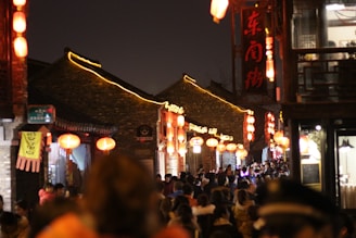A bustling street scene with local entertainment and glowing lanterns at night.