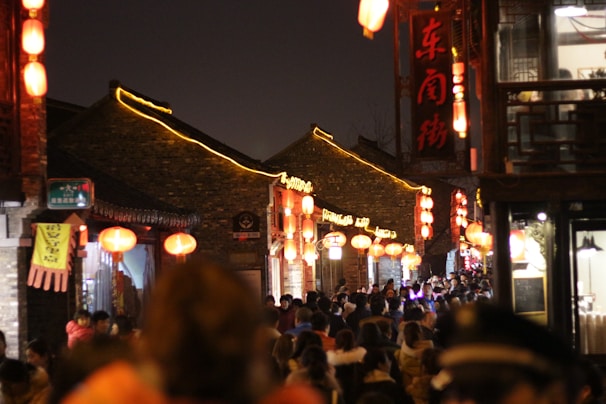 A bustling street scene with local entertainment and glowing lanterns at night.