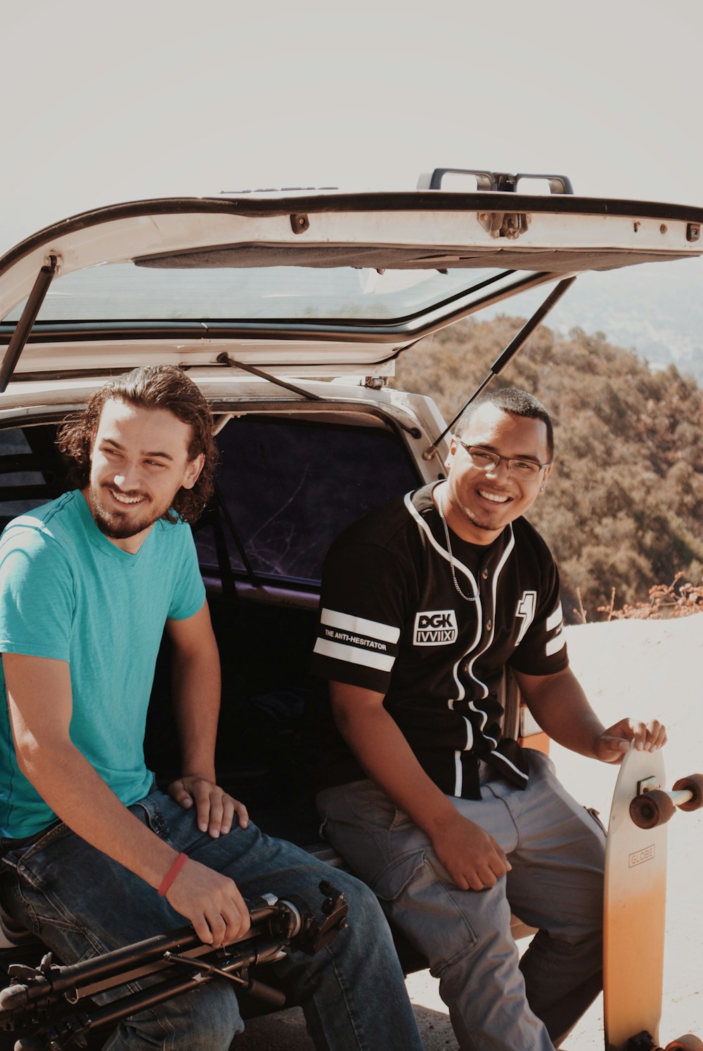 two men sitting on back of vehicle at daytime